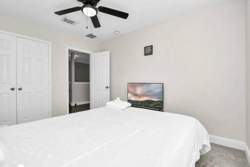 a white bedroom with a white bed and a ceiling fan at Tranquil 4-BR Oasis With Pool & Backyard Bliss! in Cypress