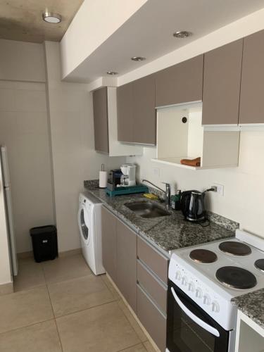 a kitchen with a stove top oven next to a washing machine at Altos de Belgrano PREMIUM in Salta