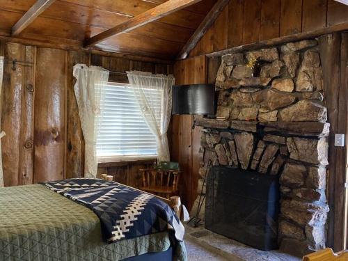 2410 - Oak Knoll Duplex Studio #12 cabin في بيغ بير لاكي: غرفة نوم مع موقد حجري وسرير في غرفة