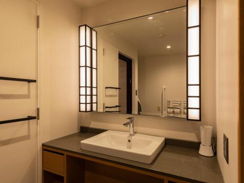 a bathroom with a sink and a large mirror at Tokyu Stay Hida Takayama Musubinoyu in Takayama