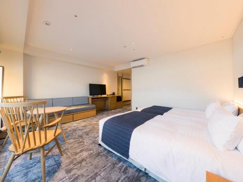 a hotel room with a bed and a table and chair at Tokyu Stay Hida Takayama Musubinoyu in Takayama