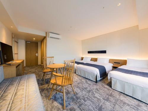 a hotel room with two beds and a table and chairs at Tokyu Stay Hida Takayama Musubinoyu in Takayama