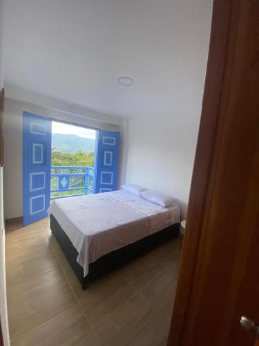 1 dormitorio con 1 cama y puerta azul en Apartahotel Villa Carolina 4, en Jericó