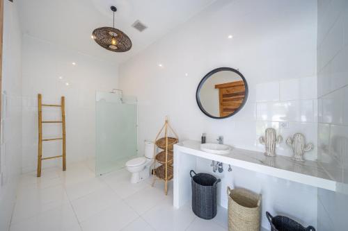 a white bathroom with a sink and a mirror at Villa Primarosa - Charming 2BR Villa in Pererenan in Munggu