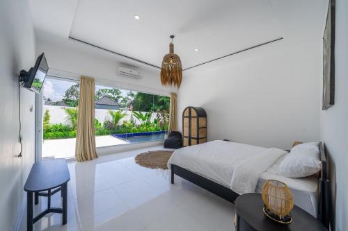 a bedroom with a bed and a large window at Villa Primarosa - Charming 2BR Villa in Pererenan in Munggu