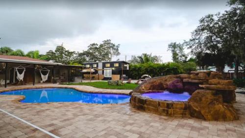 a backyard with a swimming pool and a rock fountain at 108 Tiny House Bradenton in Bradenton