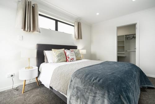 a white bedroom with a large bed and windows at Stunning 3 bedrooms house in Hillcrest - Close to Waikato University & Cambridge in Hamilton