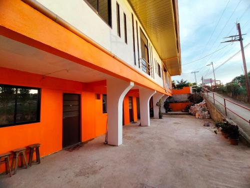 an orange building with tables and chairs next to it at Aunora Rooms 