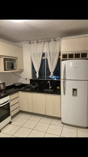 a kitchen with a white refrigerator and a window at Apartamento próximo do aeroporto internacional in São José dos Pinhais