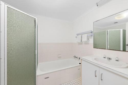 a white bathroom with a tub and a sink at Seaspray Unit 3 4 Intrepid Close in Nelson Bay