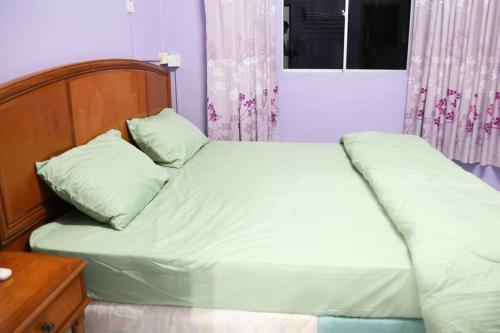 a bedroom with a bed with a wooden headboard at Kuhara Court Apartment Suite in Tawau