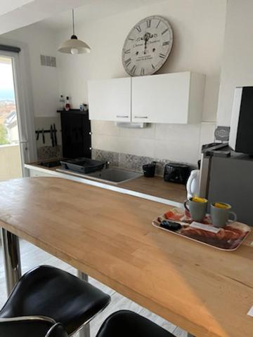 une cuisine avec une table et une horloge au mur dans l'établissement La plénitude Appt 124, à Sens