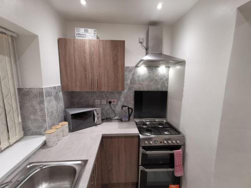 una piccola cucina con piano cottura e lavandino di Three Bedroom Modern Apartment by Luton Airport and Luton Station a Luton