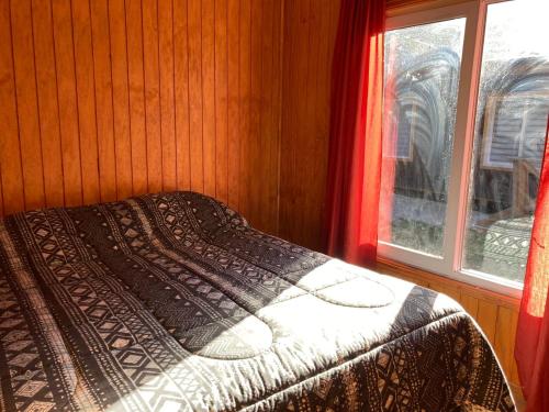 Cama en habitación con ventana en Cabañas Las Márgaras Uno, en Llanquihue