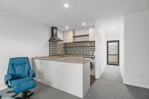 a kitchen with a counter and a blue chair at Dicks Place - Alexandra Holiday Home in Alexandra