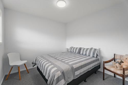 a bedroom with a bed and a chair at Dicks Place - Alexandra Holiday Home in Alexandra