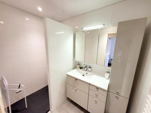 une salle de bain blanche avec un lavabo et un miroir dans l'établissement Appartement T3 avec terrasse, garage - La Chaume - FR-1-92-765, à Les Sables-dʼOlonne
