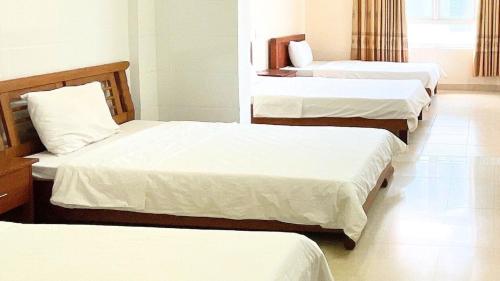 Habitación con 3 camas y sábanas blancas. en Khách sạn 206 en Da Nang