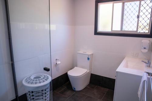 a bathroom with a toilet and a sink and a window at The Rec Hotel Waroona in Waroona