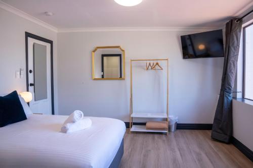 a bedroom with a white bed and a mirror at The Rec Hotel Waroona in Waroona