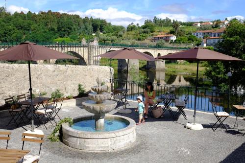 a child standing in front of a fountain with umbrellas at Hotel Os Poetas in Ponte da Barca