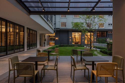 dziedziniec ze stołami i krzesłami oraz trawnikiem w obiekcie Pranakorn Heritage Hotel w mieście Bangkok