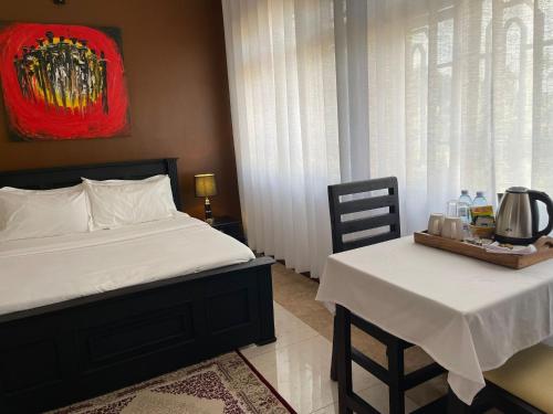 a bedroom with a bed and a table and chairs at The Jewel and the Lake in Jinja
