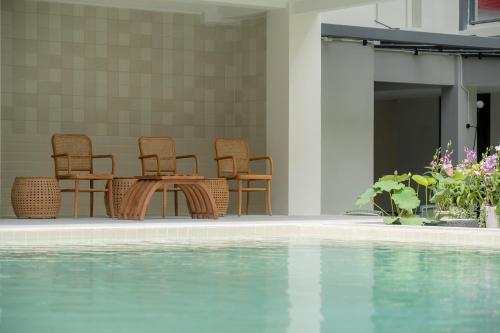 a table and chairs next to a swimming pool at Pranakorn Heritage Hotel in Bangkok