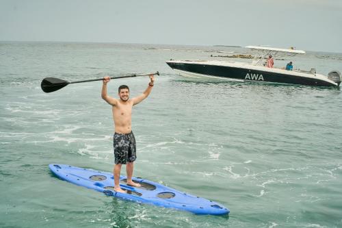 Ein Mann steht auf einem Paddelbrett im Wasser in der Unterkunft Mangata Beach in Cartagena de Indias