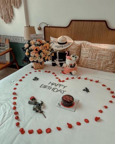 a bed with a happy anniversary cake and flowers on it at The Mansion Hoi An by Minova in Hoi An