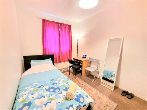 a bedroom with a bed and a desk with a pink window at London Rooms in London