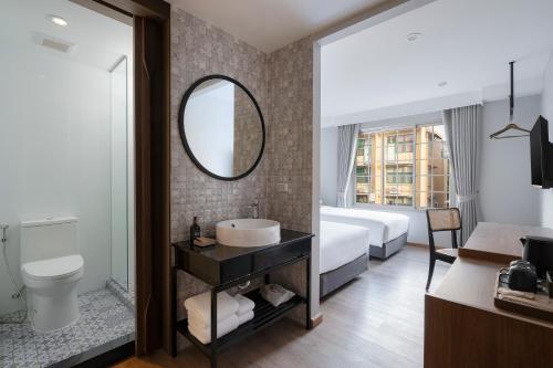 a bathroom with a sink and a bed and a mirror at Pranakorn Heritage Hotel in Bangkok