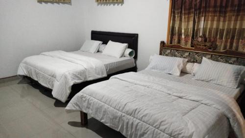 2 camas en una habitación con sábanas blancas en Ocean Holiday liukang, en Bira