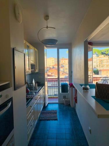 une cuisine avec un sol en carrelage bleu et une grande fenêtre dans l'établissement Studio cocooning, à Nice