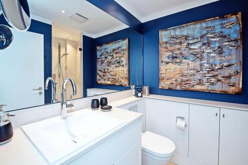 ein Badezimmer mit blauen Wänden, einem Waschbecken und einem WC in der Unterkunft Haus Norderhoog Wohnung 67 - "Zoe's Nest"  in Westerland
