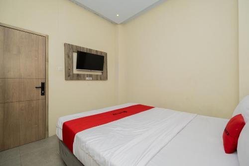 um quarto com uma cama e uma televisão na parede em RedDoorz @ Sangnala Homestay Pakisaji em Malang