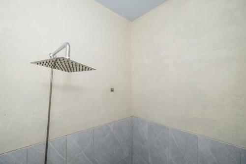 um chuveiro num quarto branco com uma cabeça de chuveiro em RedDoorz @ Sangnala Homestay Pakisaji em Malang