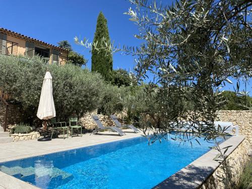 une piscine avec un parasol et des chaises à côté d'une maison dans l'établissement Grande villa rénovée avec piscine, clim et Wi-Fi au coeur du Luberon - FR-1-708-61, à Saint-Saturnin-lès-Apt