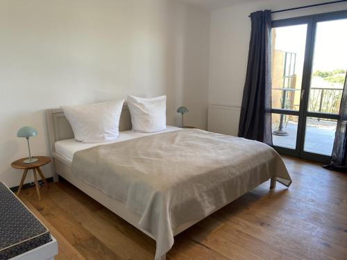 une chambre avec un lit avec des draps blancs et une fenêtre dans l'établissement Gîte dans villa rénovée avec piscine, climatisation et WiFi à Saint-Saturnin-lès-Apt - FR-1-708-62, à Saint-Saturnin-lès-Apt