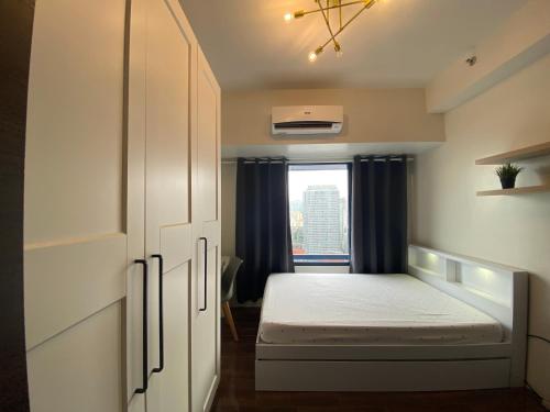 um pequeno quarto com uma cama e uma janela em Air Residences 4439 em Manila