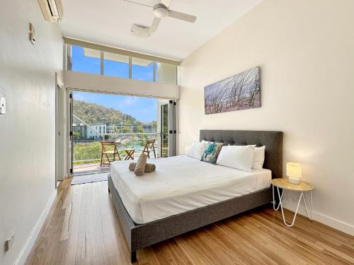 a bedroom with a bed and a large window at Waterfront Townhouse 'Beachside Apartment 16' - Central location, pool, good wifi in Nelly Bay