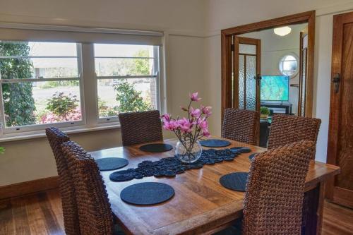 a dining room table with chairs and a vase of flowers at Stylish Family Friendly Escape in Ballarat