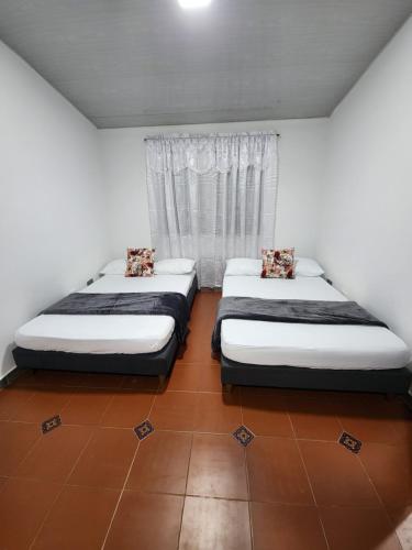 2 Einzelbetten in einem Zimmer mit Fenster in der Unterkunft Finca ARES in Filandia