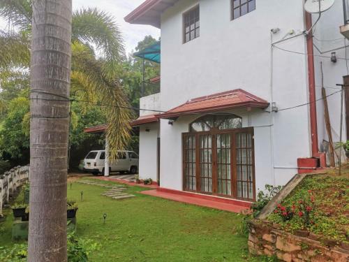 una casa blanca con una palmera al lado de un patio en Kandy ambuluwawa mount villa, en Angammana