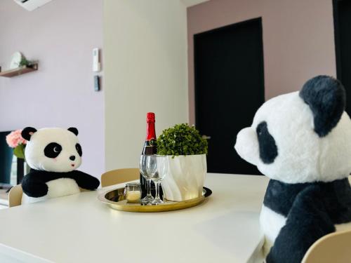 two stuffed pandas sitting at a table with a bottle of wine at New Comfy Urban Suite Homestay at Georgetown for family by Urban Staycations LOD in Jelutong