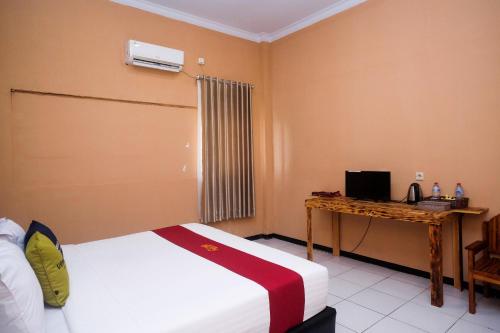 a bedroom with a bed and a desk with a computer at Urbanview Hotel L'Tefa Pemalang 