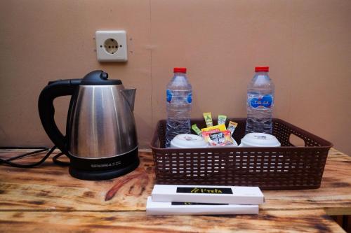 a tea kettle and two bottles of water on a table at Urbanview Hotel L'Tefa Pemalang in Padurekso