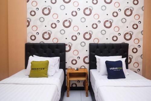 two beds sitting next to each other in a room at Urbanview Hotel L'Tefa Pemalang 