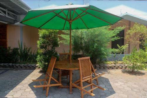 a table and chairs under a green umbrella at Urbanview Hotel L'Tefa Pemalang in Padurekso