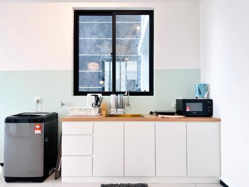 a kitchen with white cabinets and a window at New Comfy Urban Suite Homestay at Georgetown for family by Urban Staycations LOD in Jelutong